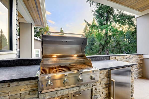 Outdoor kitchen with built in grill and stacked stone surround