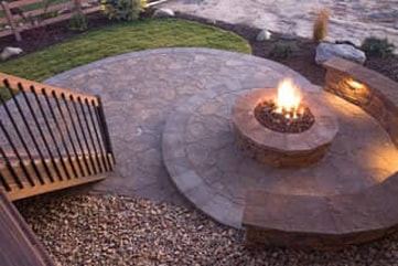 New spiral design stone paver patio with outdoor fire pit and stone seating area